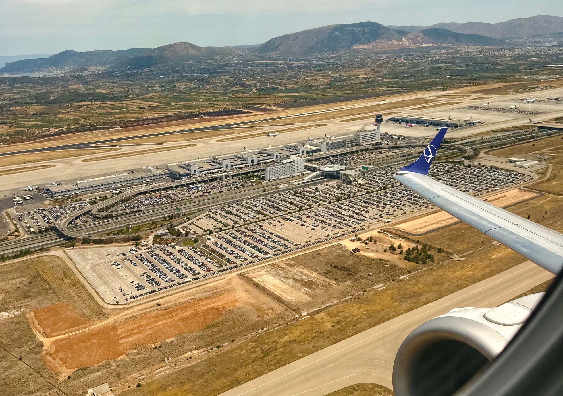 Athens Airport - aerial view. Runway, terminals, planes, and service vehicles. Grey clouds in the sky.