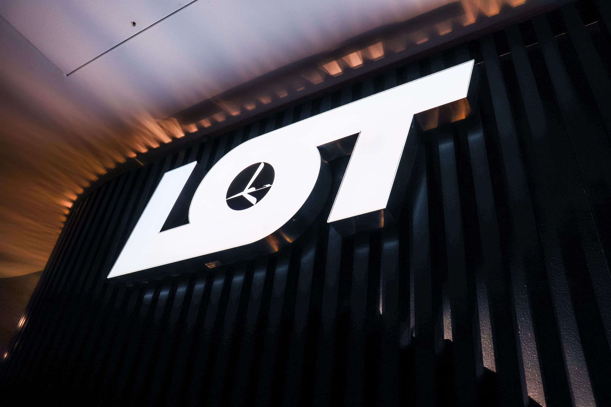Large white LOT logo on a dark wall lit from below