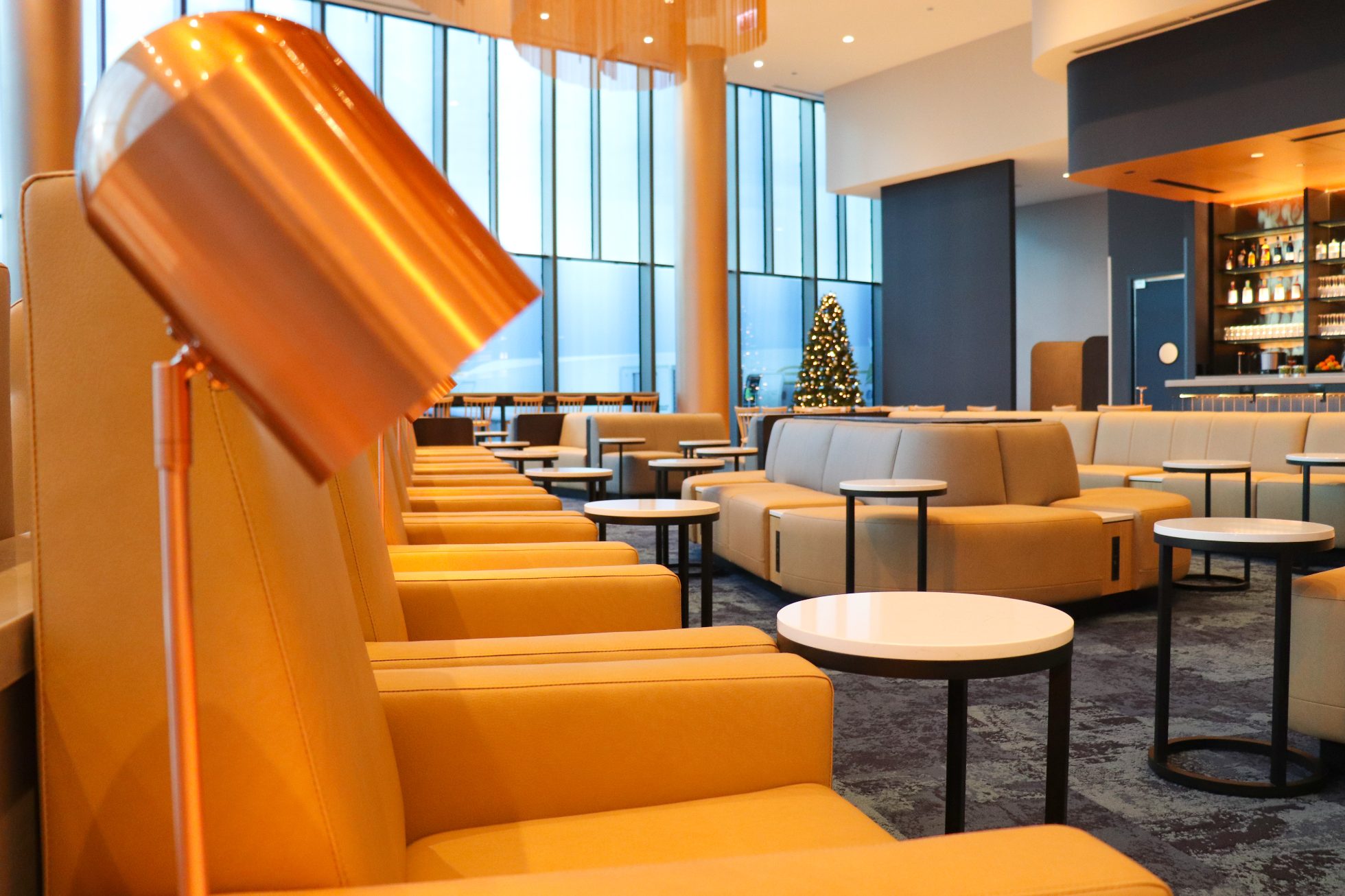 Comfortable orange armchairs, small round tables beside them, space in the business lounge in Chicago.