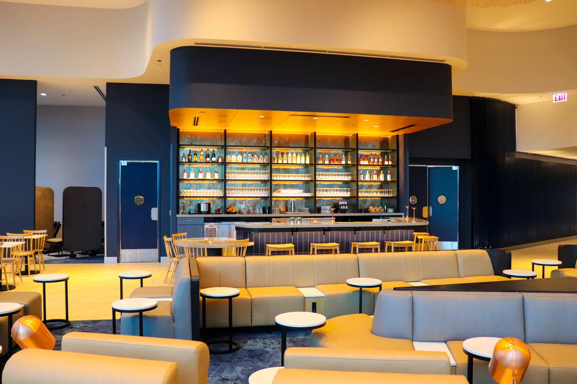 Elegant bar in a business lounge at Chicago airport on a navy wall, with warm elegant lighting and chairs around the bar