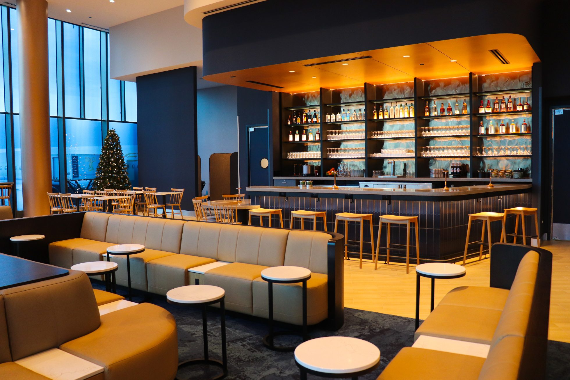 Elegant bar in a business lounge at Chicago airport on a navy wall, with warm elegant lighting and chairs around the bar