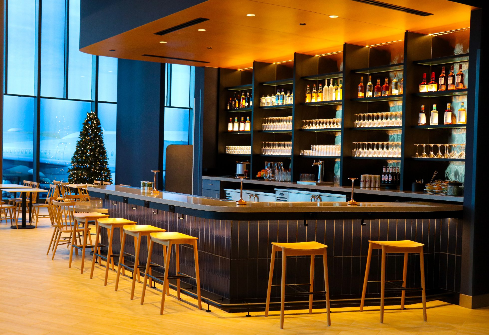 Elegant bar in a business lounge at Chicago airport on a navy wall, with warm elegant lighting and chairs around the bar