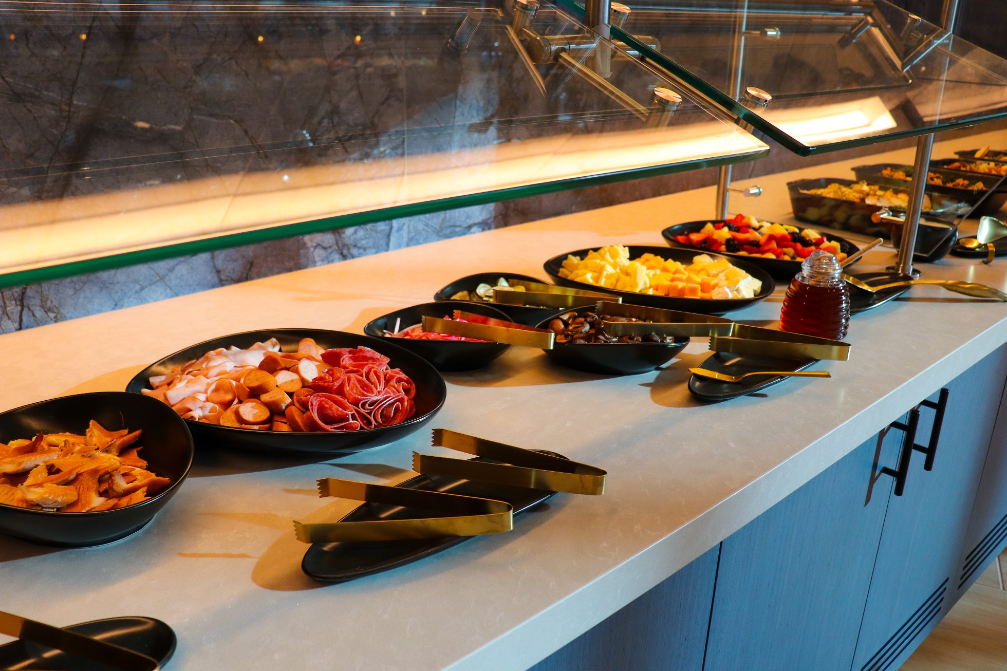 Swedish buffet with dishes served in black platters on white countertops - Business Lounge Chicago