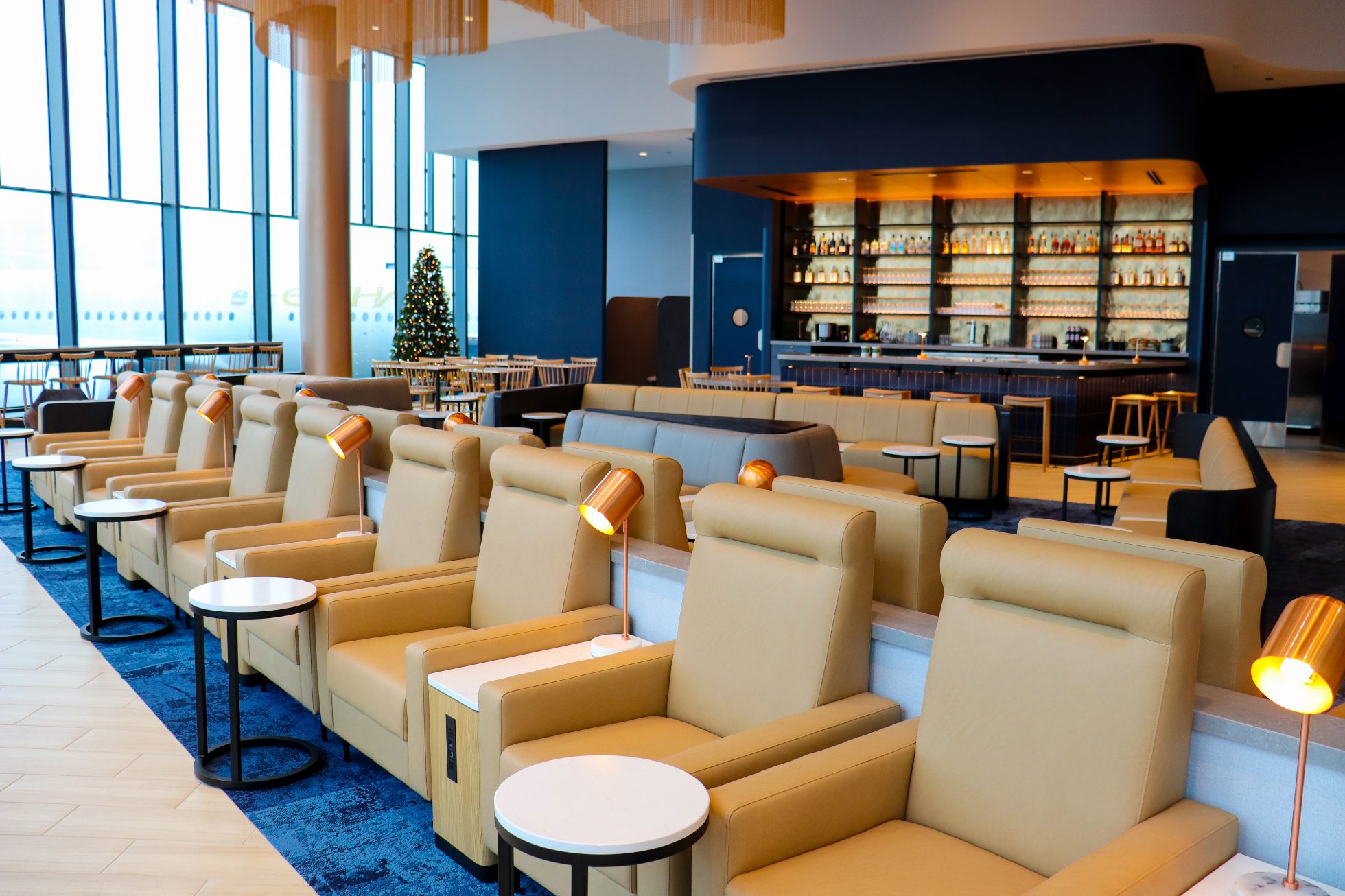 A row of beige armchairs facing a panoramic window with a view of the Chicago airport tarmac.