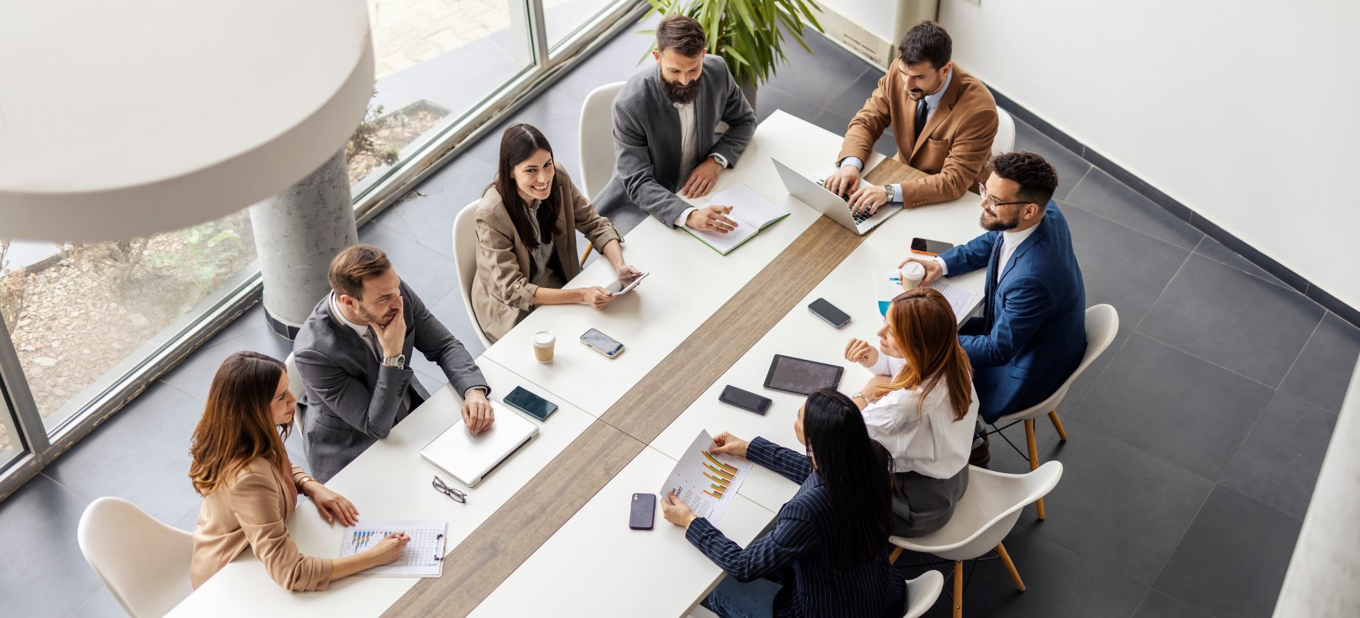 From above view of leadership team sitting and conference table at boardroom and having meeting.