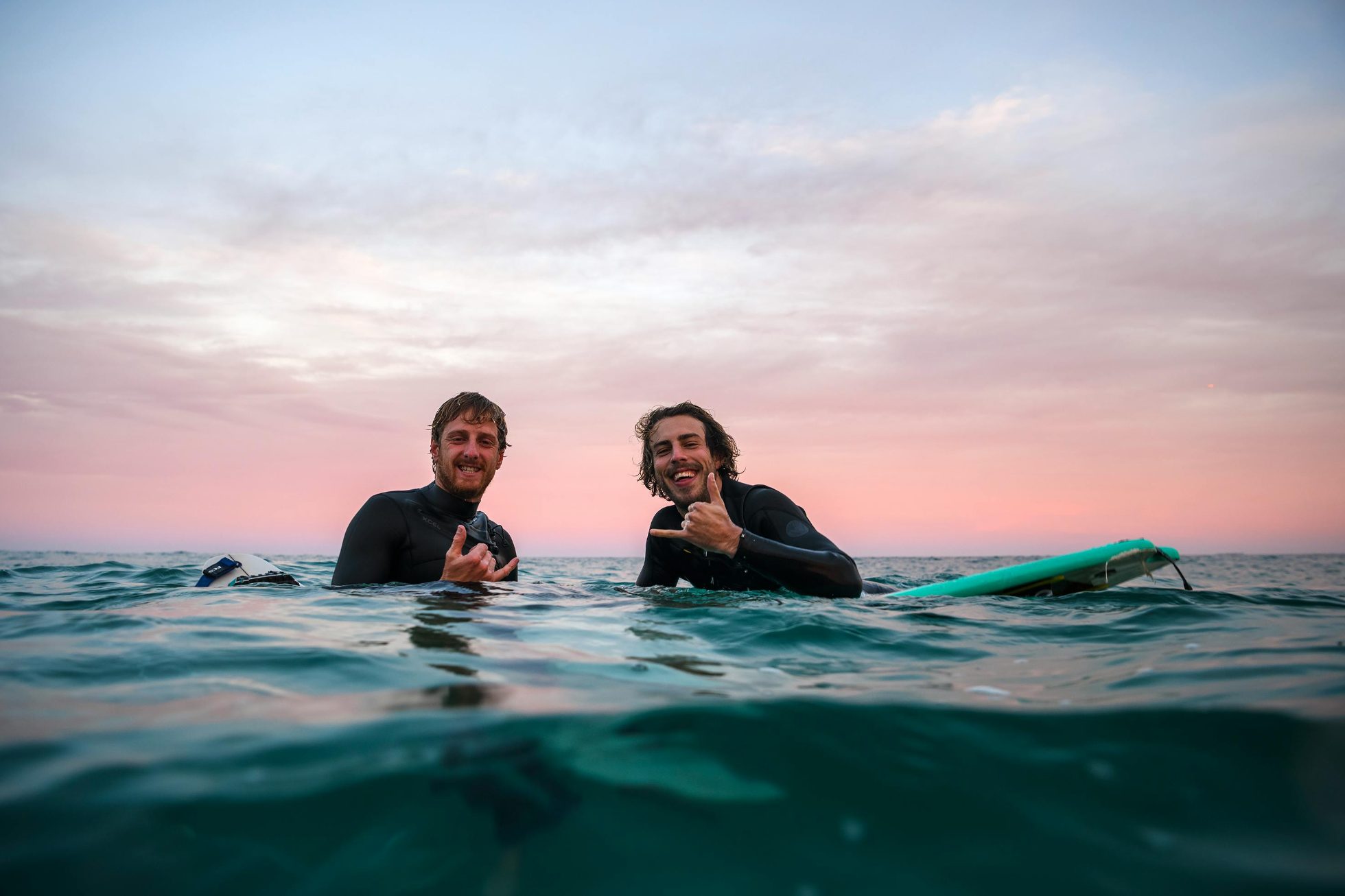 Dwóch młodych surferów pozuje do zdjęcia w wodzie 