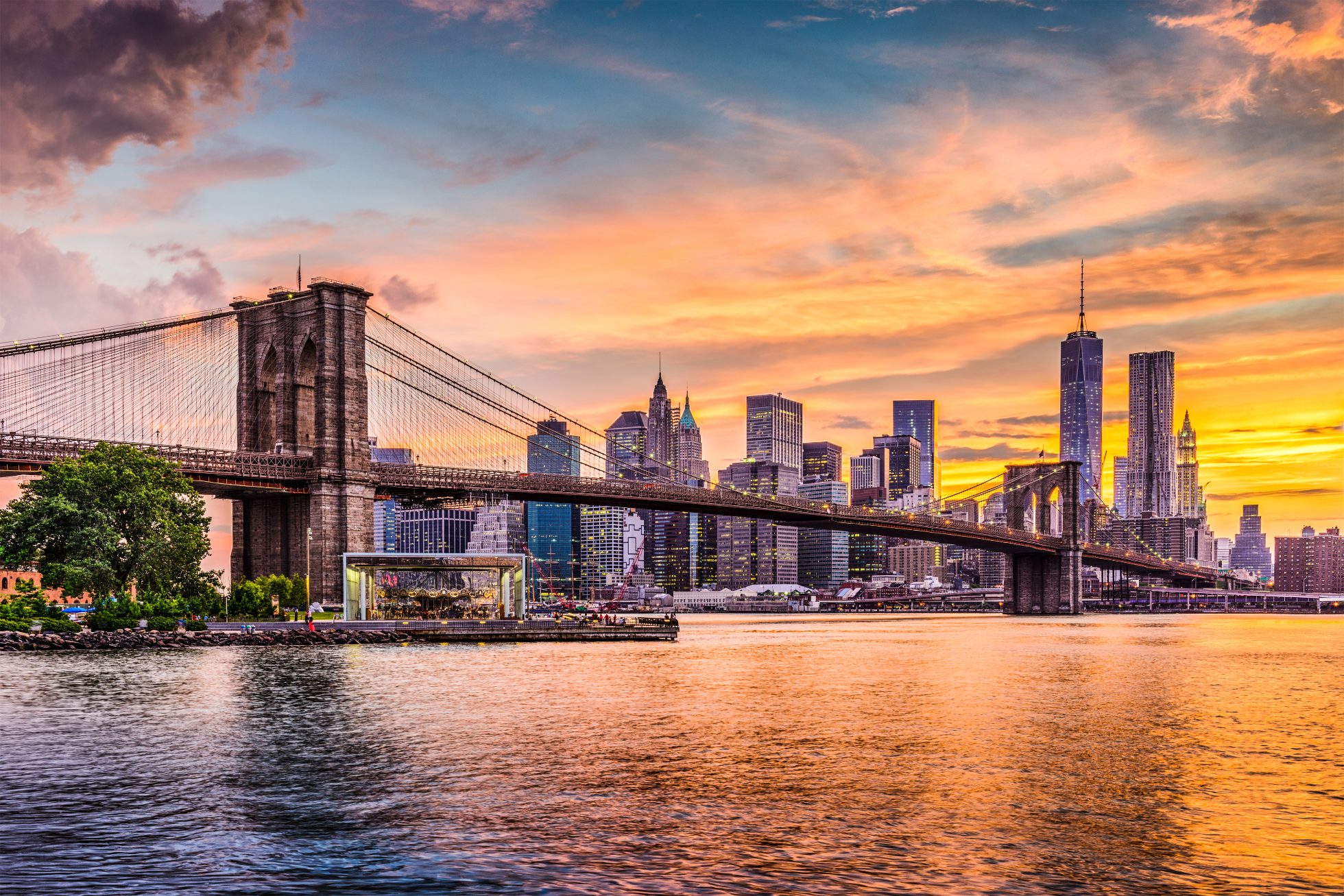 Skyline von New York City am East River mit Brooklyn Bridge bei Sonnenuntergang.