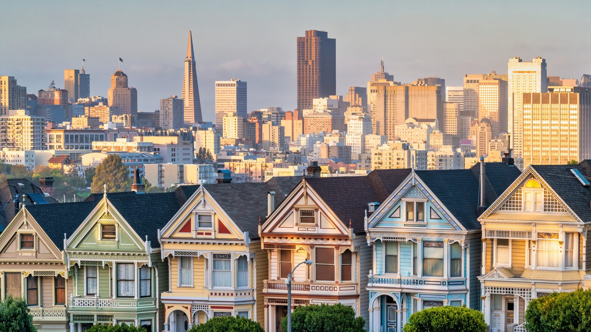 The famous Painted Ladies houses and the San Francisco skyline in California, USA during sunset.