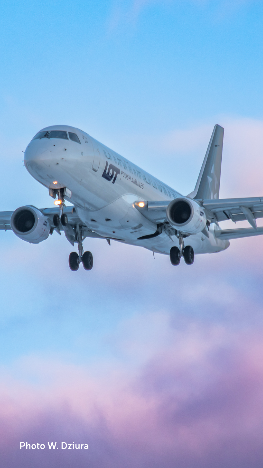 LOT's Embraer 175 aircraft with the Star Alliance logo floating in the blue and pink sky