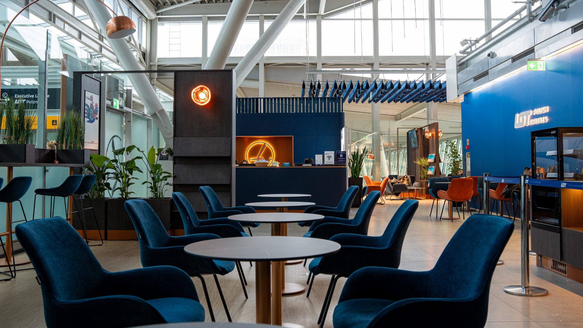 LOT Business Lounge Polonez - Reception, open space with tables and armchairs in navy blue.