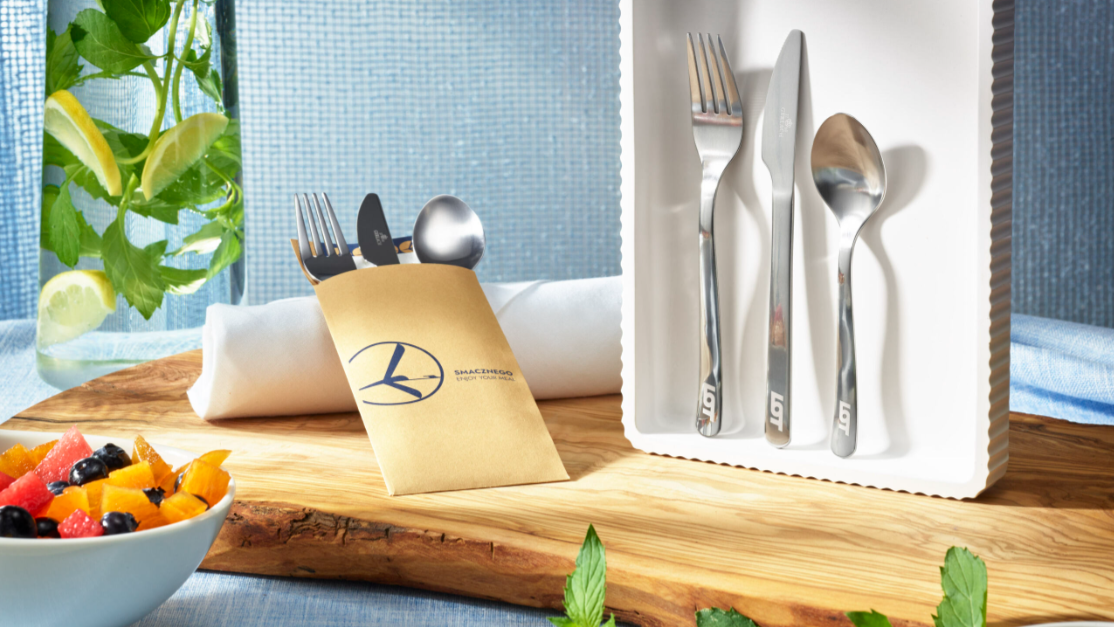 Silver cutlery on a white napkin holder on an airplane.