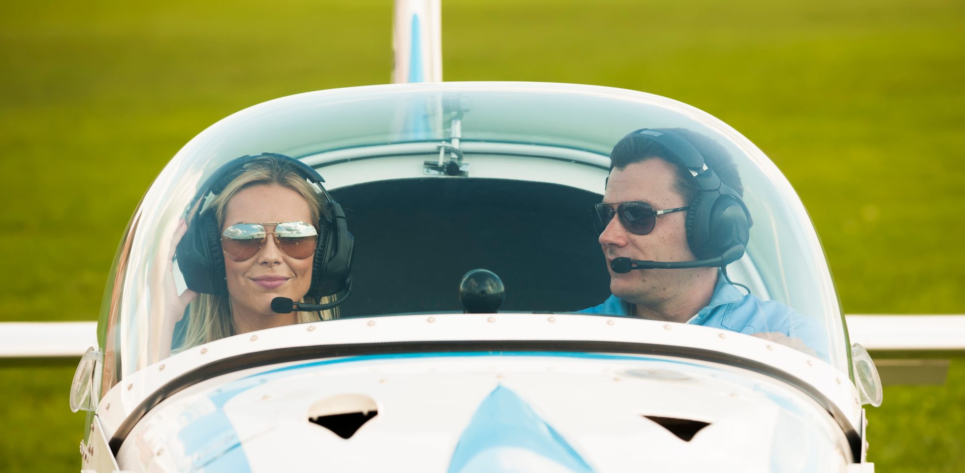 Woman and man pilot at airplane, looking at camera, preparing for flying