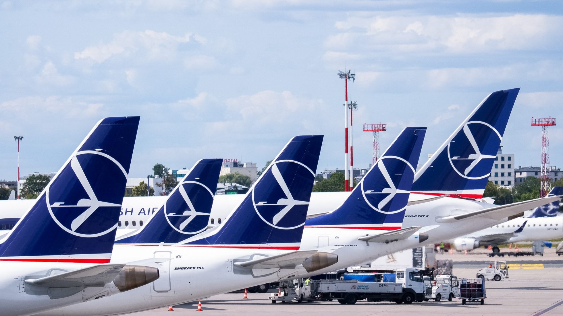 five horizontal stabilisers of LOT aircraft with the crane logo lined up at Chopin Airport on a sunny day