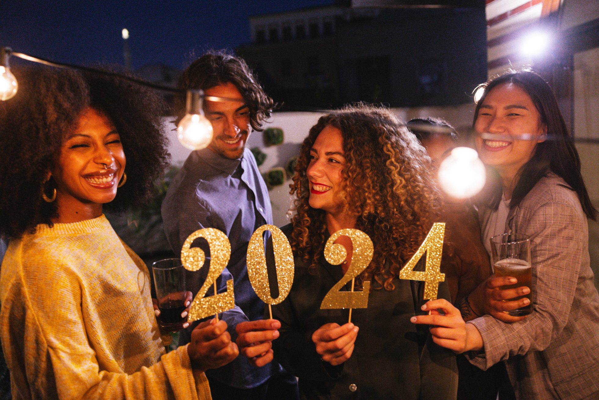 Group of friends holding the number 2024, celebration conceptual image for New Yearâs Eve.