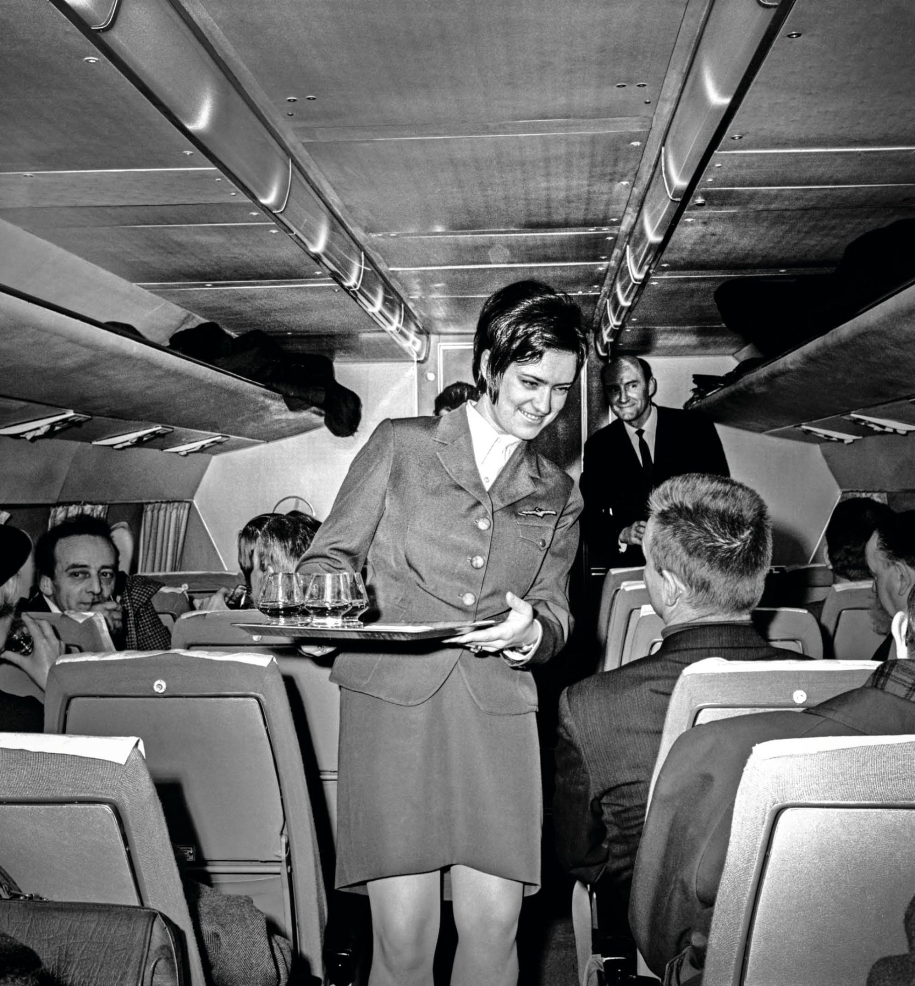 Stark schwarz-weißes Foto einer Stewardess bei der Arbeit im Flugzeug.