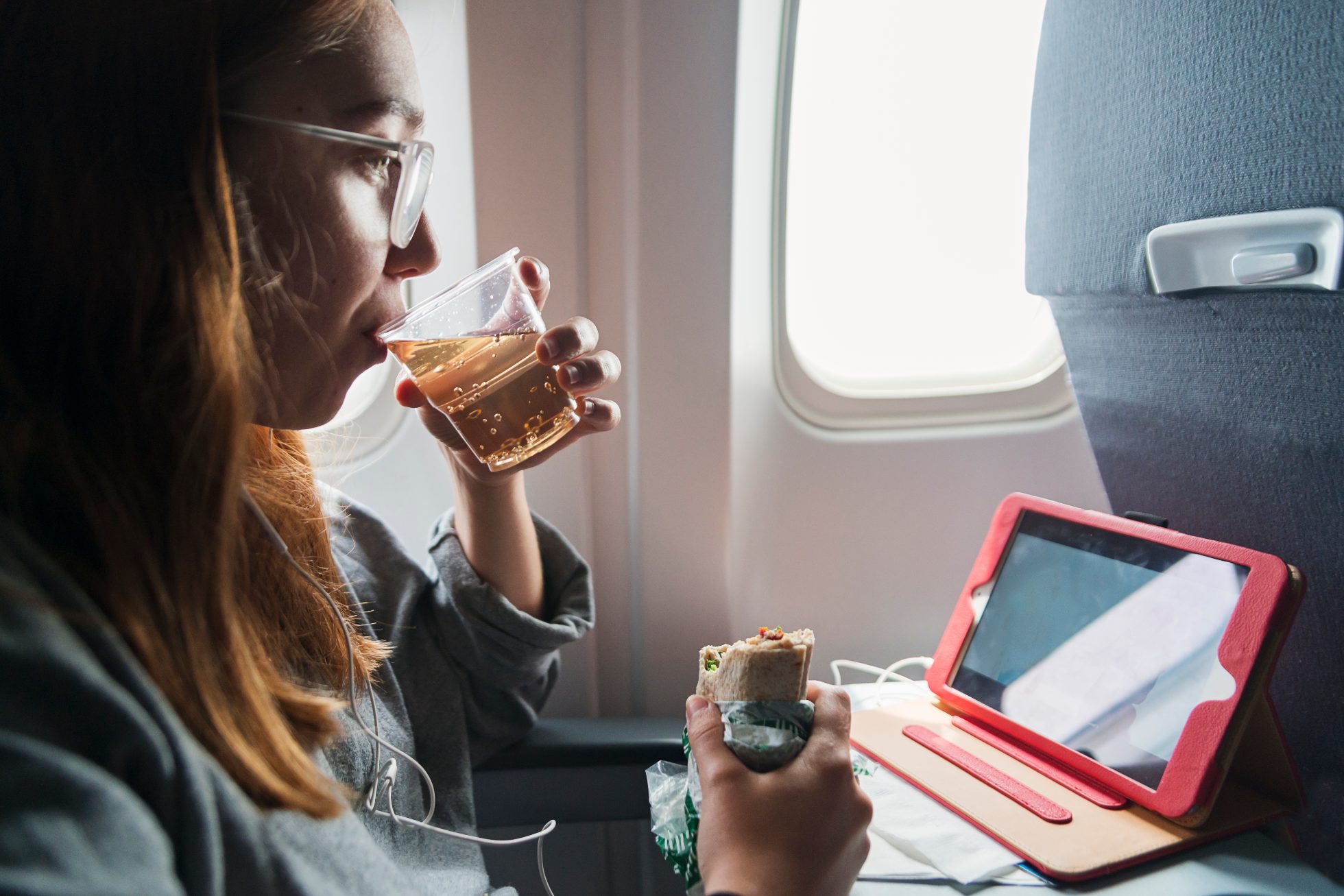 Woman eating a meal and drinking juice on board an airplane