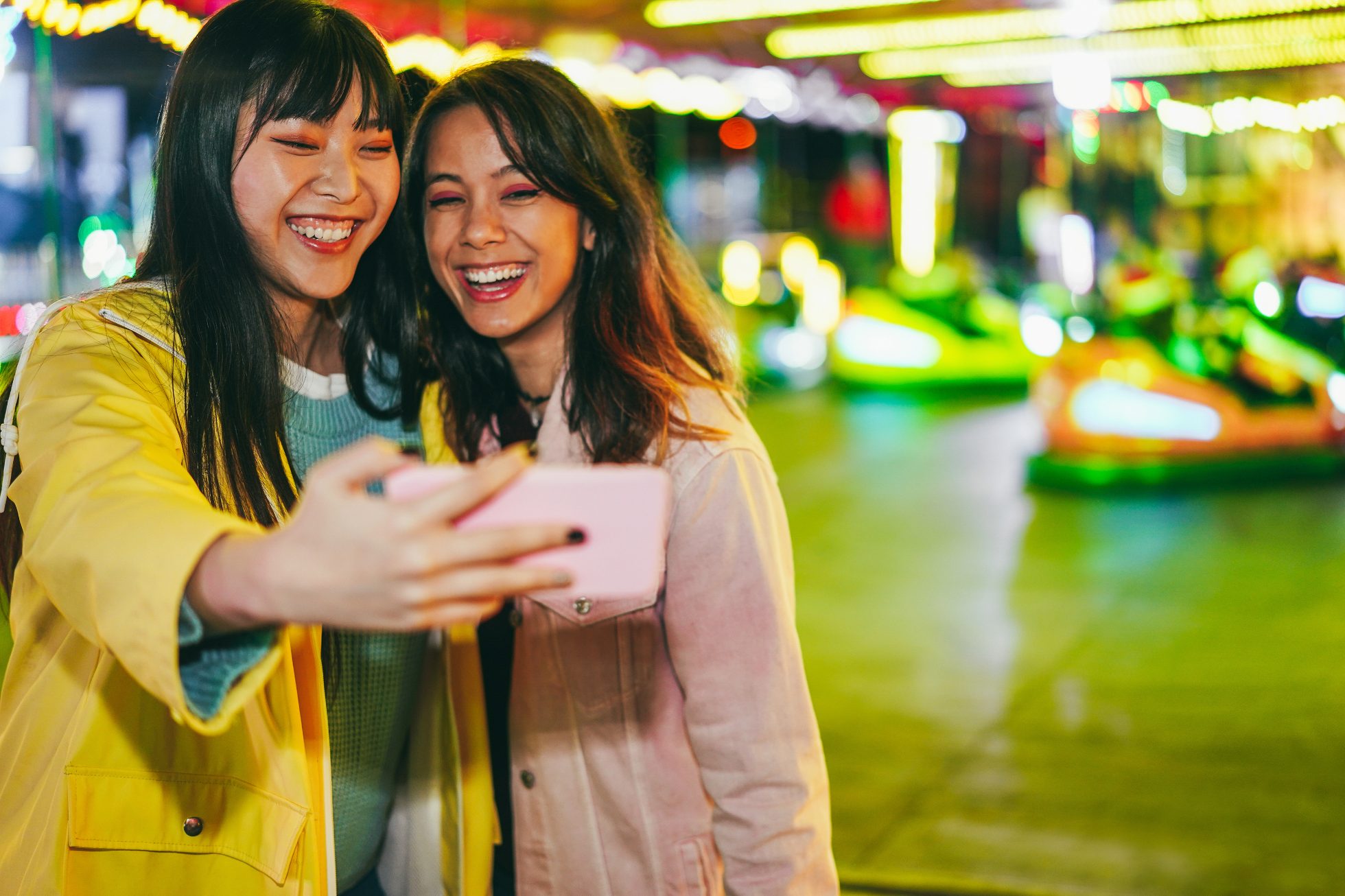 Happy asian girls having fun doing selfie outdoors at amusement park - Focus on left girl eye