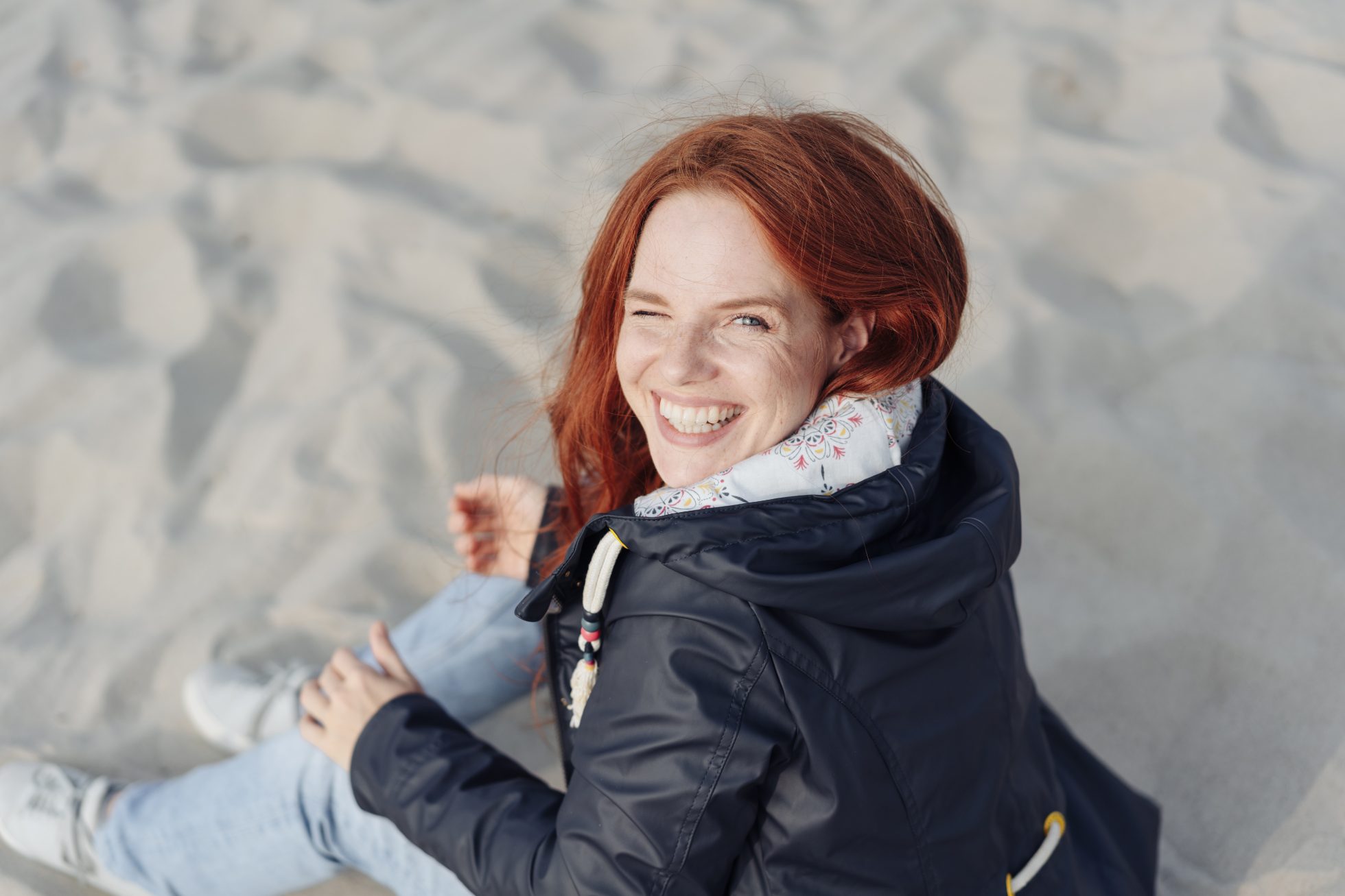 Smiling woman in a jacket on the beach