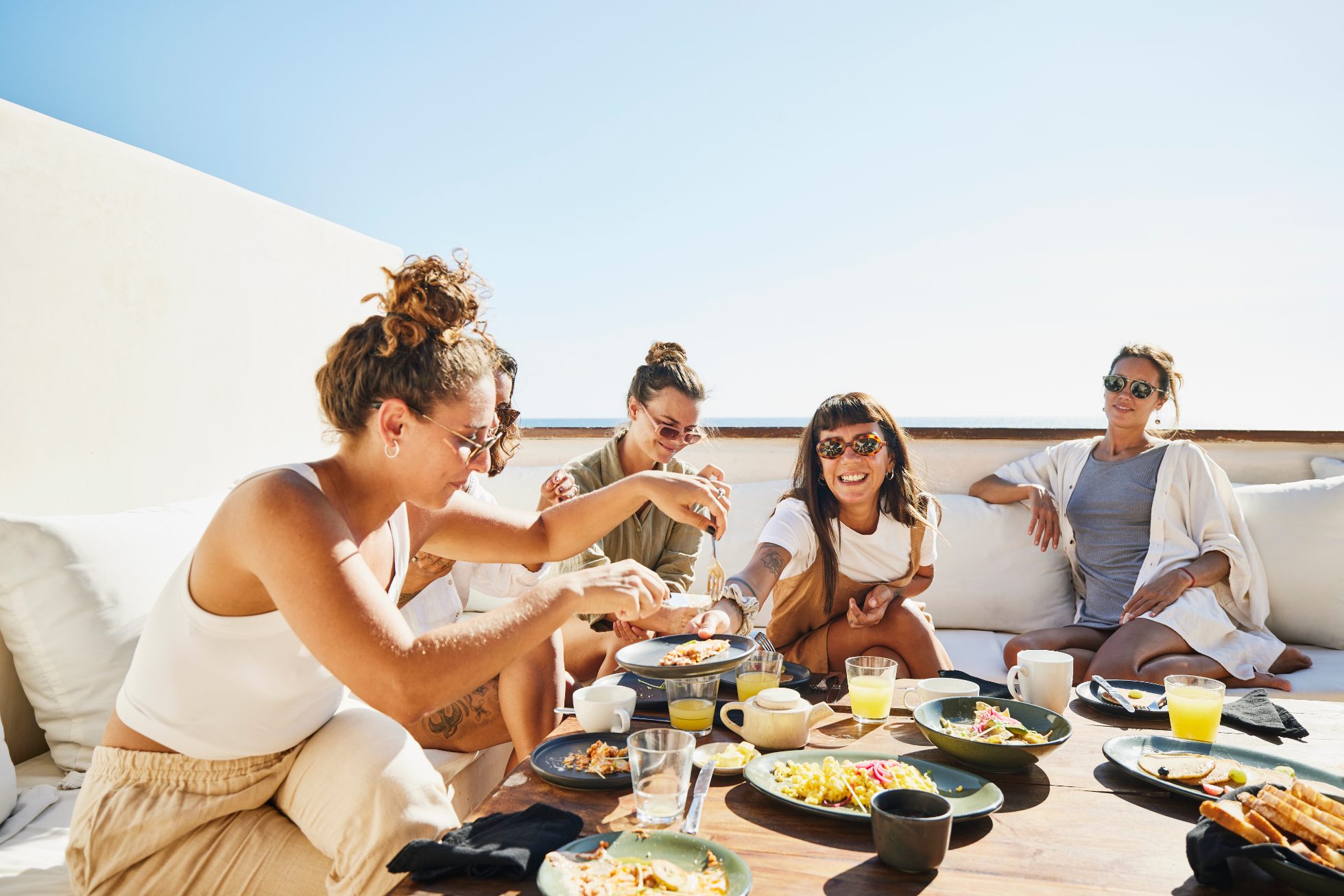 Happy young girls eat on terrace on sunny day, group trips vs solo trips