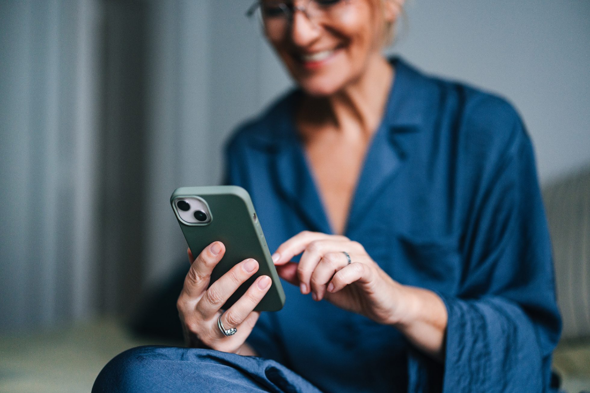 Wesoła kobieta przegląda coś w telefonie 