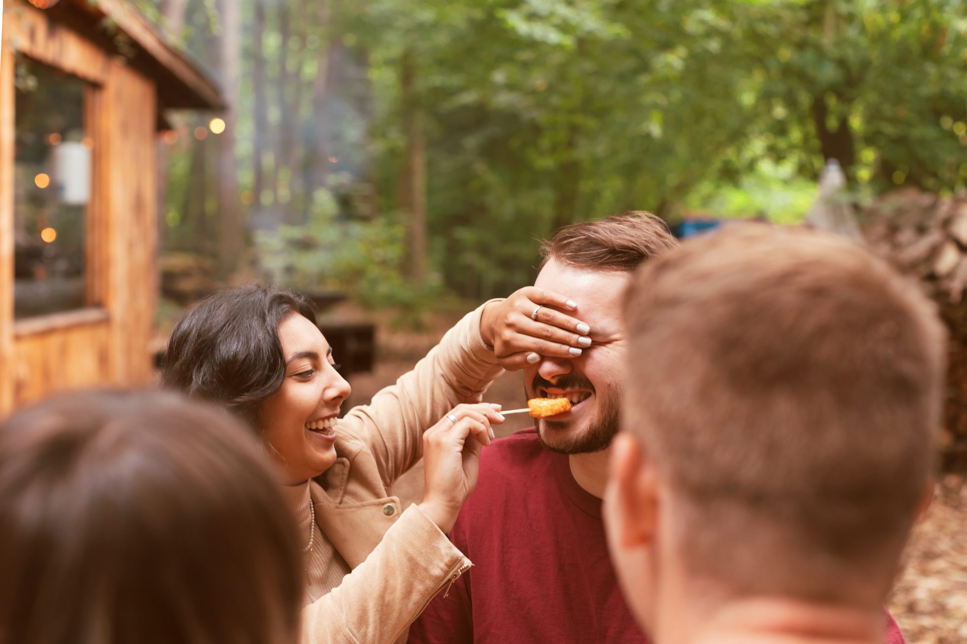 Woman blindfolding a man and feeding him a bite of food