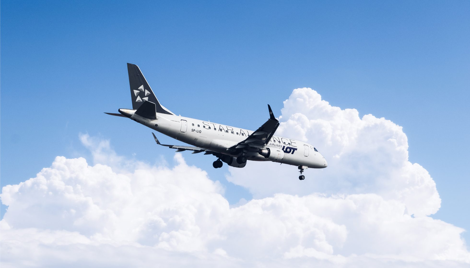 Embraer 175 aircraft in Star Alliance livery against a backdrop of clouds and blue sky