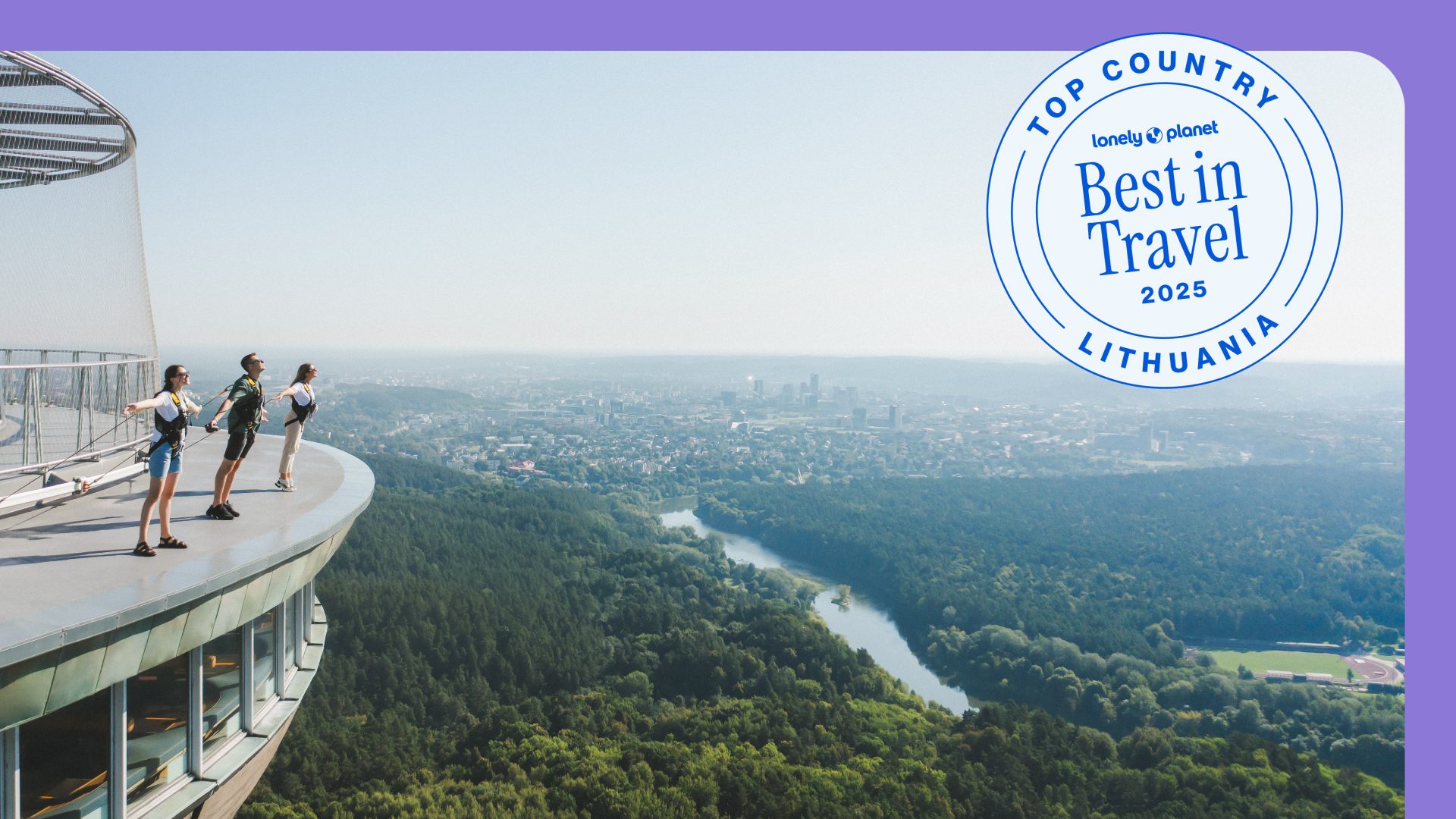 People on the edge of the Vilnius TV Tower with a city view.