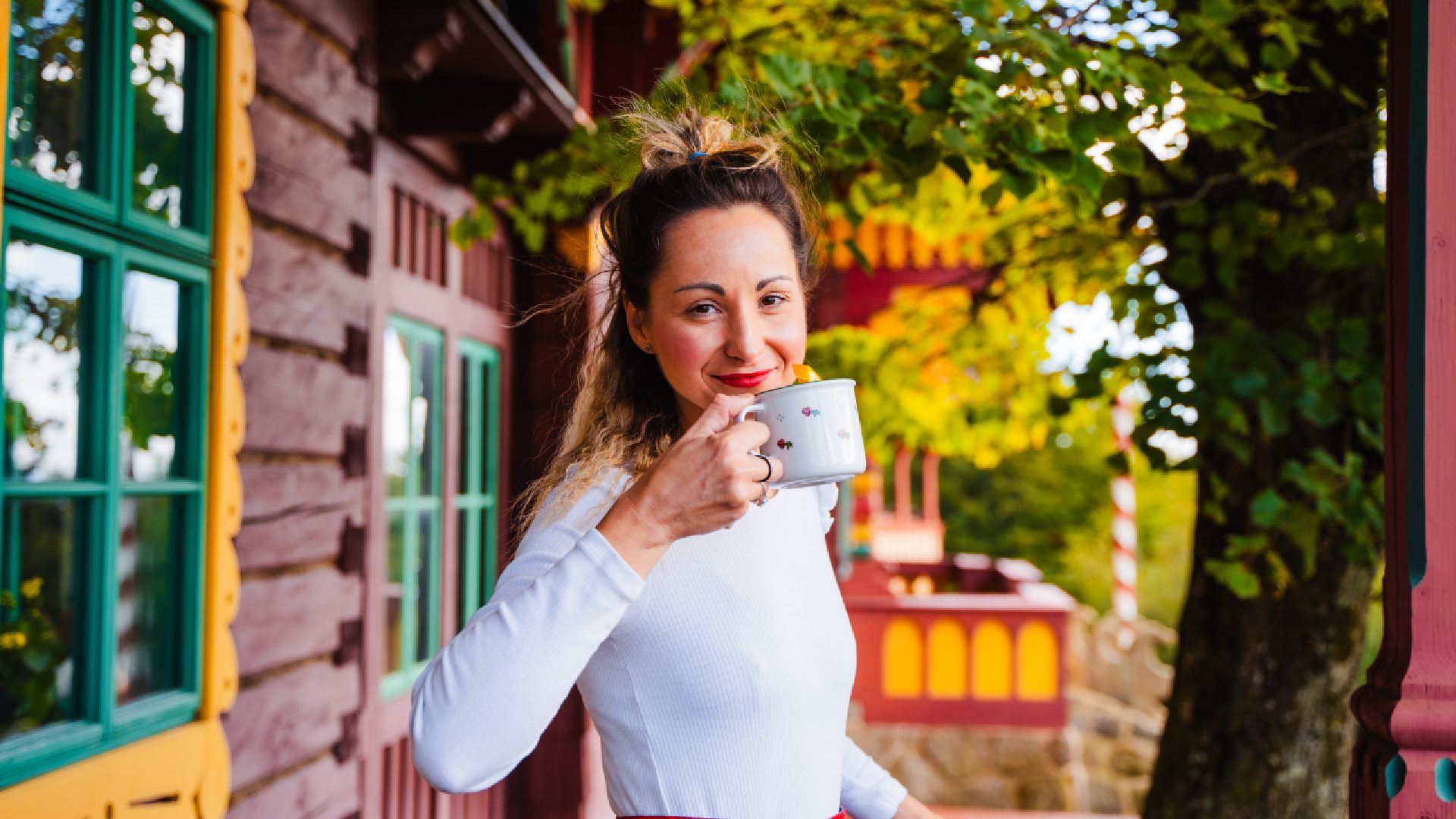 Kobieta pijąca napój przed drewnianym domkiem w Ostrawie