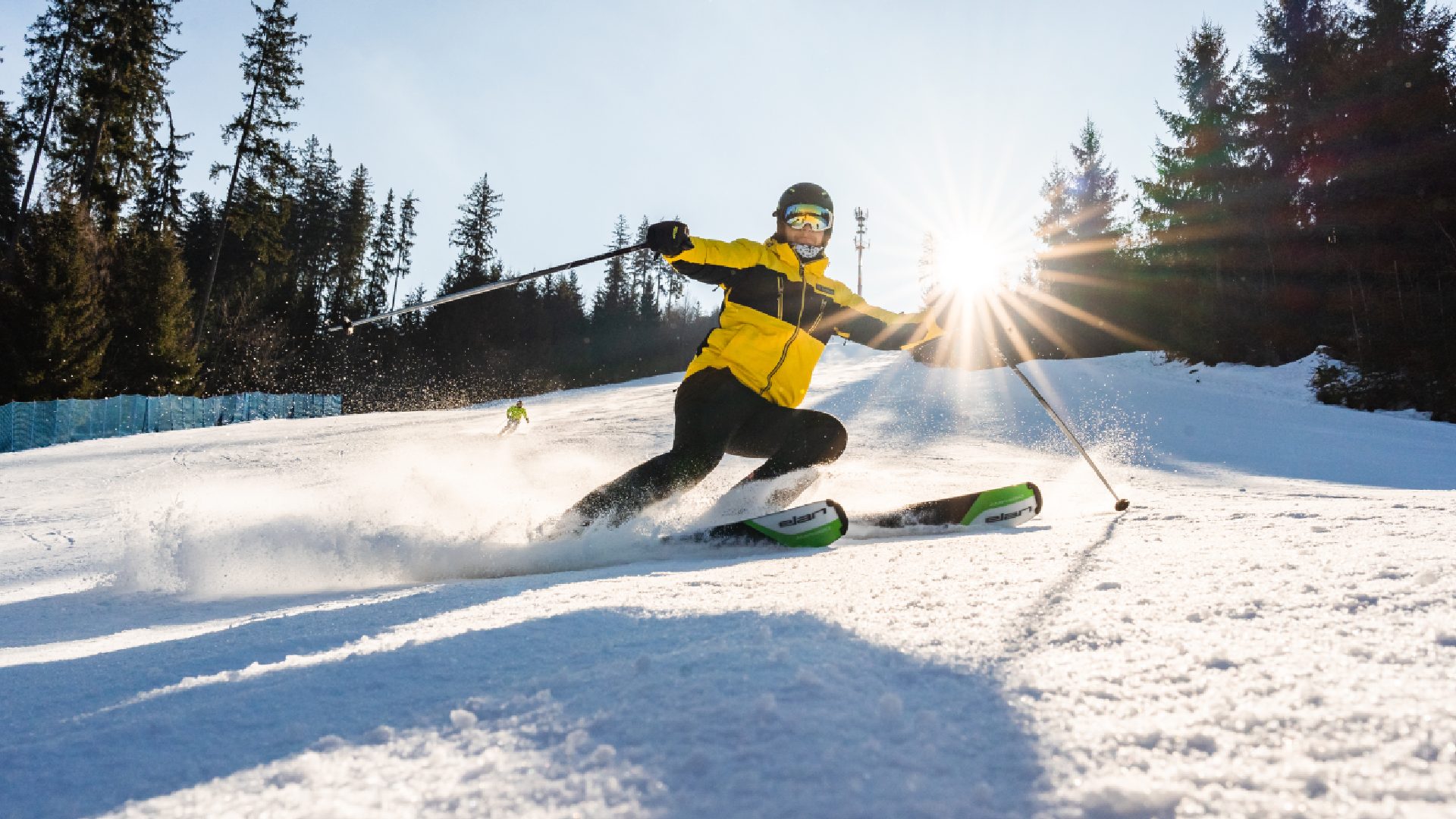 A skier in a yellow jacket descends a ski slope in Czechia