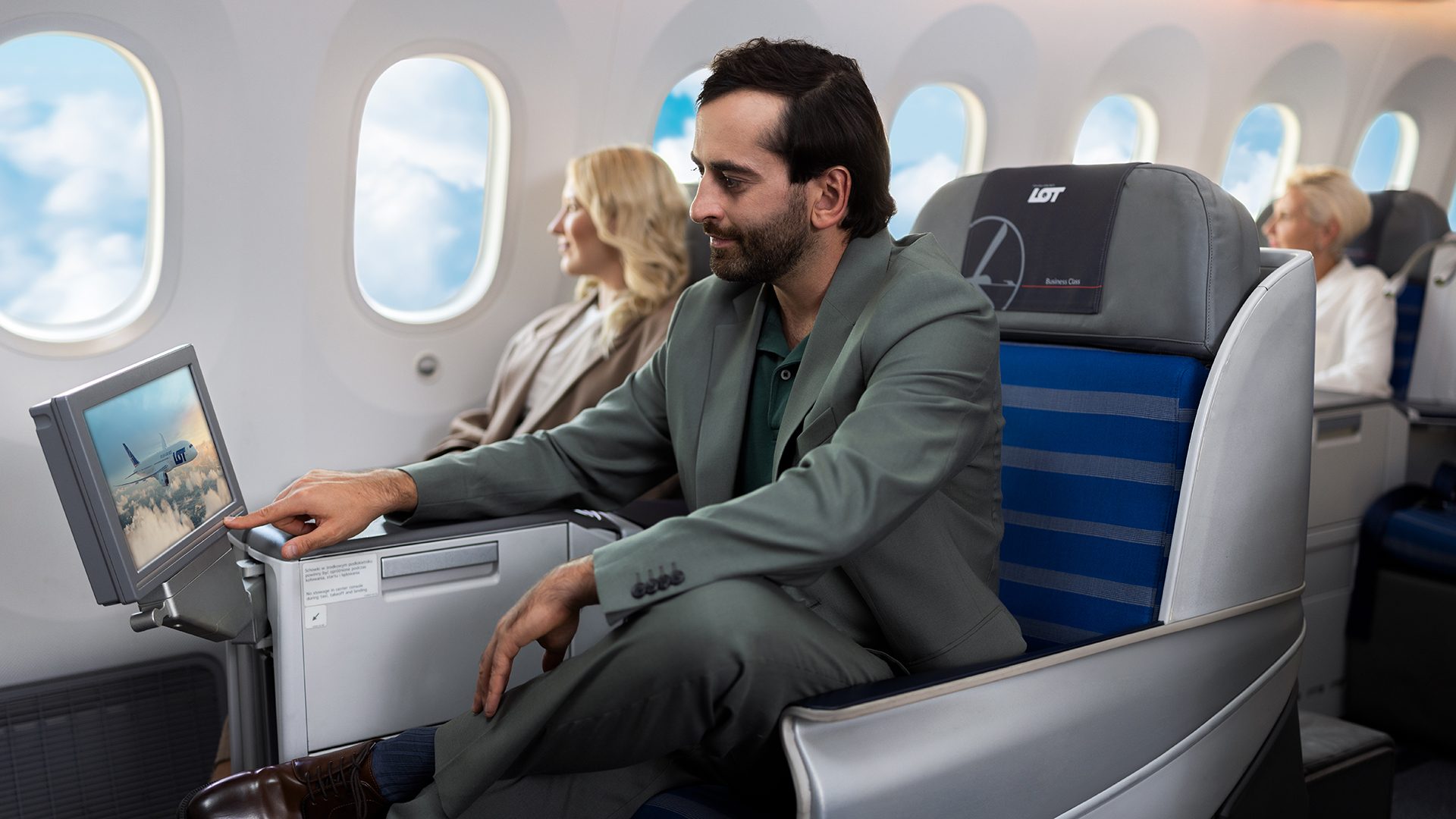 Passenger in LOT Business Class looking at screen with IFE ( in-flight entertainment)
