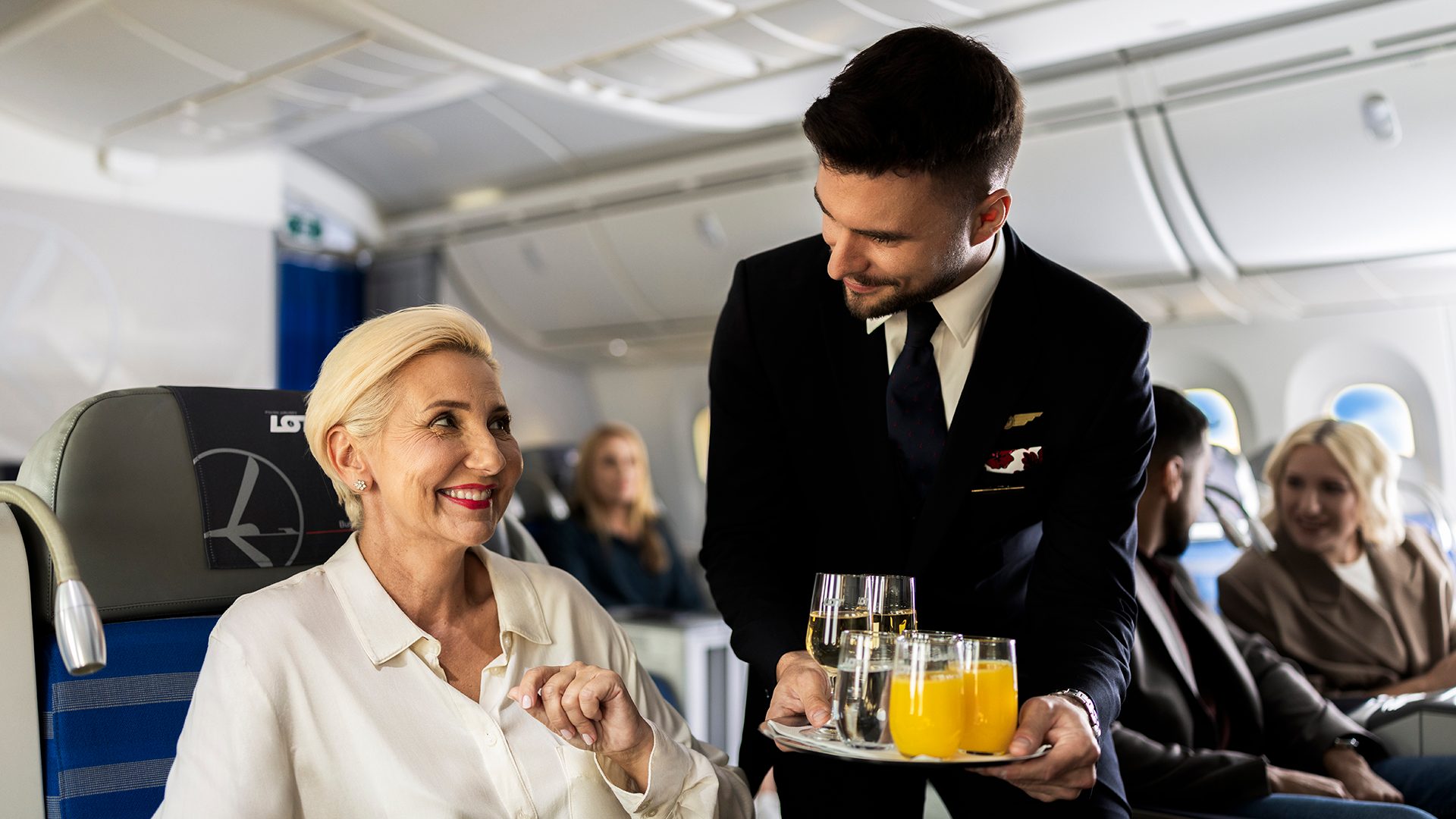 Steward serwujący napije pasażerce w LOT Business Class na pokładzie Dreamlinera