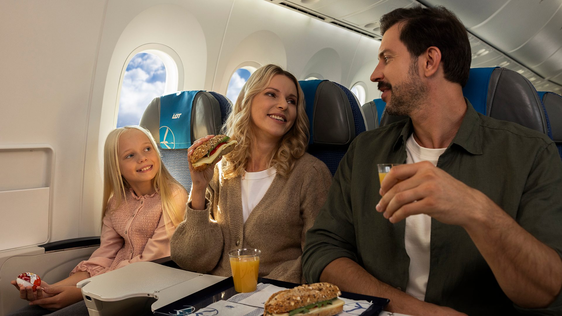 Pasażerowie jedzący kanapki i pijący sok z oferty Skybar na pokładzie samolotu Dreamliner