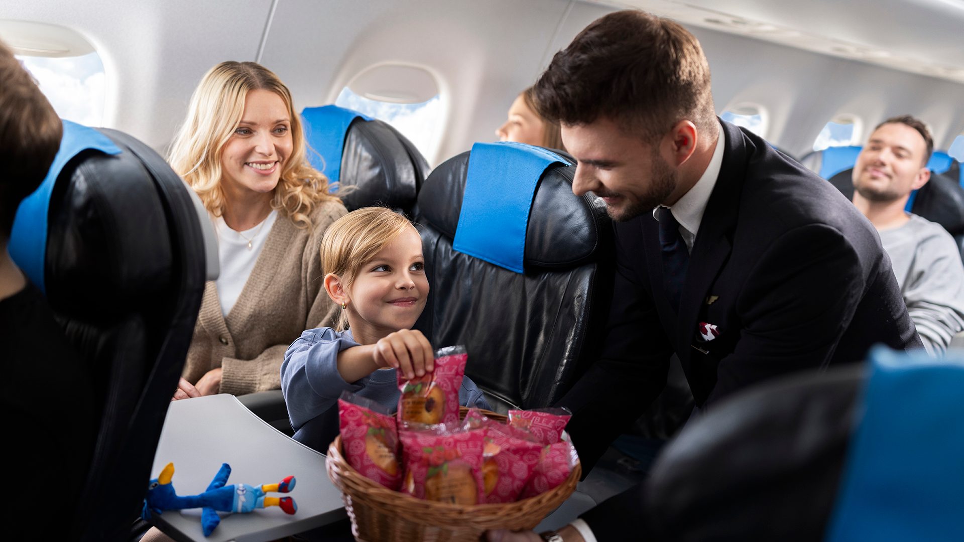 A steward serves pastries to a child aboard an Embraer