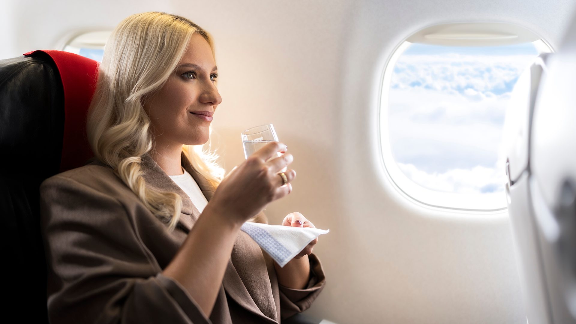 A passenger aboard an Embraer drinks a beverage 